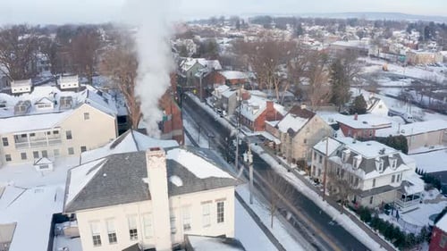 Snow falls during winter freeze, cold snowy morning. Aerial establishing shot of small town communit