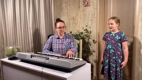 Woman Plays Piano with Child Singing