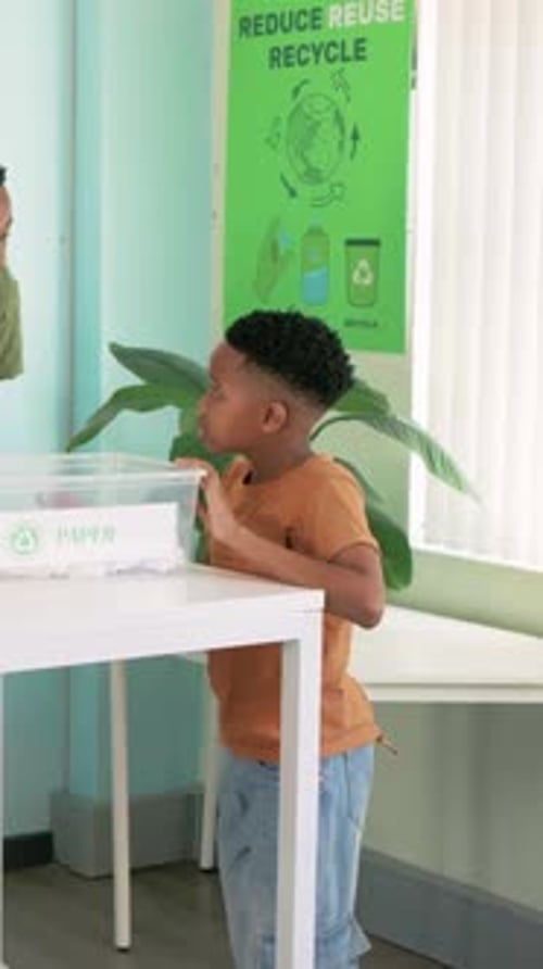 Vertical video: Lifting PAPER bin after peer gesture, youth in rust tee presenting at school table