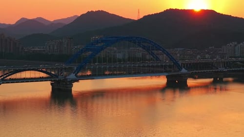 Evening Panorama of a Blue Arch Bridge with Moving Cars Over Calm Water at Sunset Hangzhou China