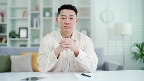 Webcam view. Asian man watching video call lesson or training while looking at camera while sitting