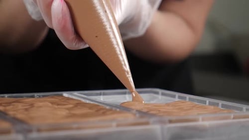 Chocolatier Pouring Melted Chocolate Into Molds in Pastry Shop Tempering Chocolate Craft Sweets