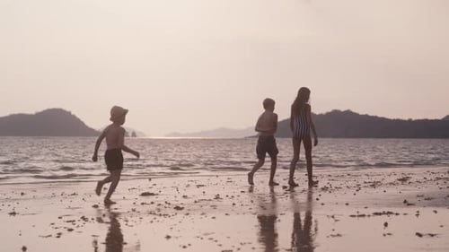 Boy Running Toward His Siblings At A Beach