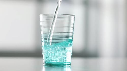 Clear Liquid Poured into Teal Glass Cup