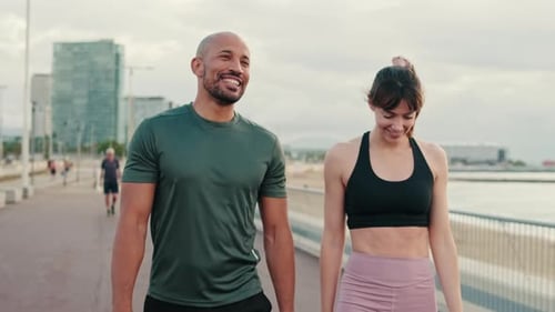 Side view of an active young sporty couple have dialog, two athletes enjoy conversation and walking