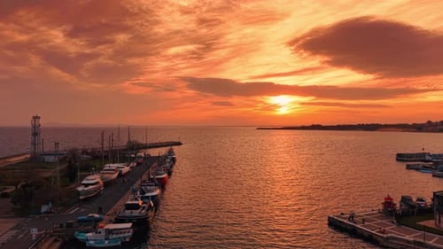 Flight along the pier with numerous boats. Setting sun colors the cloudy sky