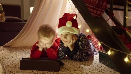 Children Watching Tablet Inside Christmas Blanket Fort