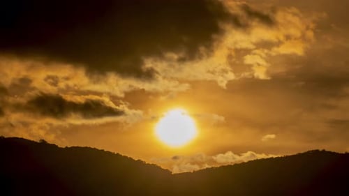 Zeitraffer des Sonnenuntergangs über wolkenbedeckten Hügeln.