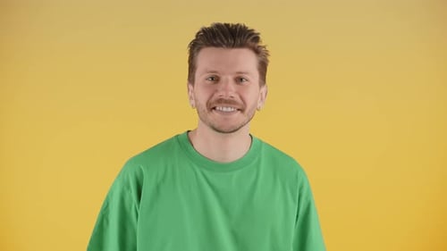 Front View of Happy Smiling Young Man Wearing Green Tshirt Isolated on Yellow Background