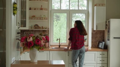 Woman Looking out Window in Bright Kitchen