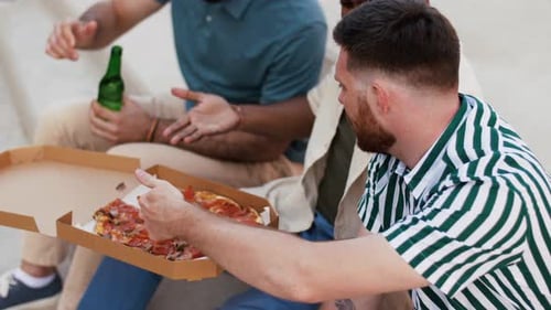 Three Young Men Share Pizza Outdoors