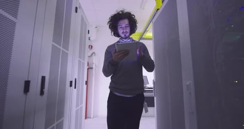 Man Inspecting Servers With Tablet in Data Center