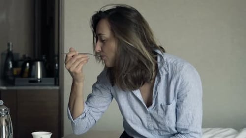 Young Pretty Businesswoman Eating Breakfast Sitting on Bed in Hotel 30s