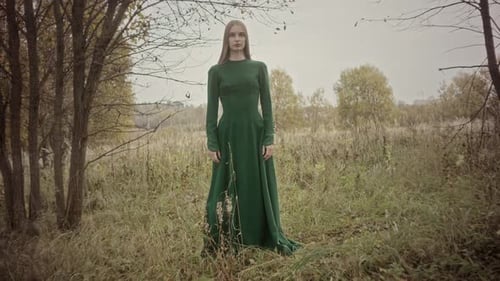 Model posing in green dress in autumn meadow