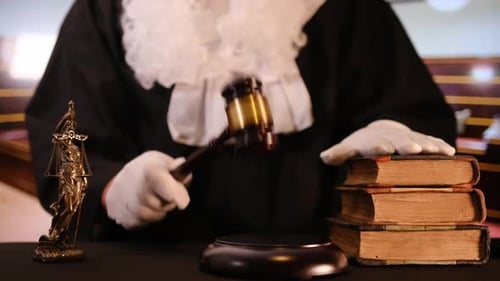 A Gavel Strikes Down in a Courtroom Setting Symbolizing Justice and Legal Authority with Law Books