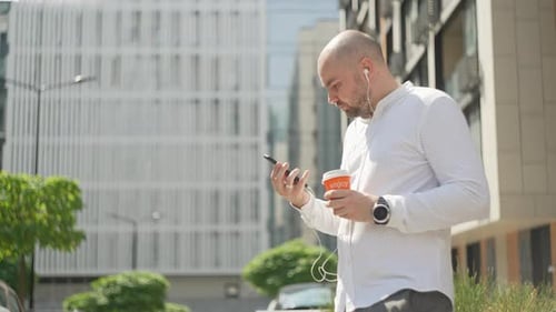 Man Using Phone and Drinking Coffee Outdoors