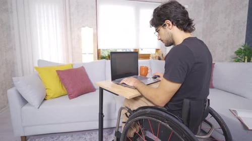Adult in Wheelchair Working on Laptop at Home