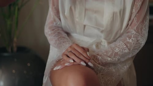 Woman's Hands with Engagement Ring Wearing White Robe