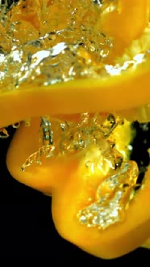 Geschnittene gelbe Paprika fallen unter das Wasser, gefilmt mit einer Hochgeschwindigkeitskamera mit 1000 Bildern pro Sekunde
