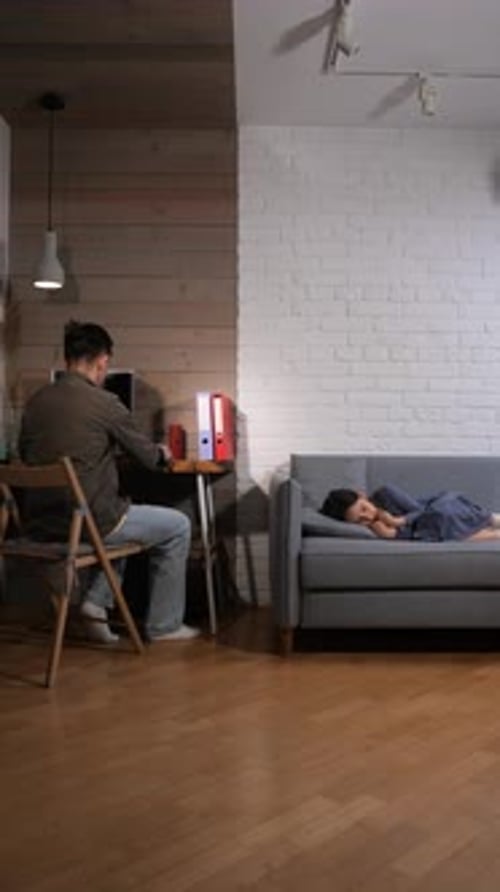 Vertical Video Man Working on a Laptop at His Home Office Desk Late at Night Balancing Work with
