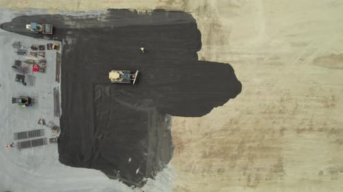 Aerial shot of road construction workers and road construction machinery making pavement