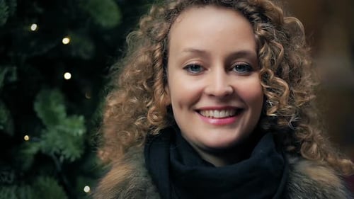Smiling Young Woman near Christmas Tree