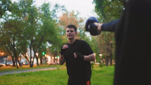 Young Athlete Practicing in Park Man Sparring in Park with Trainer at Sunset Male Boxer Training