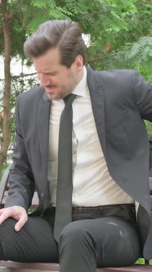 Man in Suit on Bench Experiences Back Pain