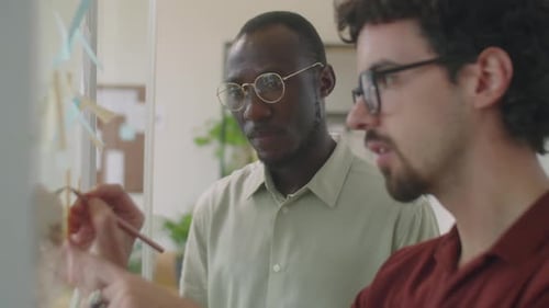 Multiethnic Colleagues Using Sticky Notes at Work in Office