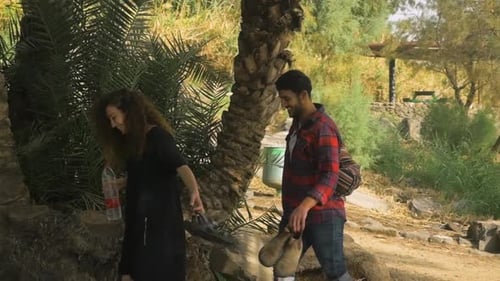 A couple of lovers walk among palm trees - camera transition