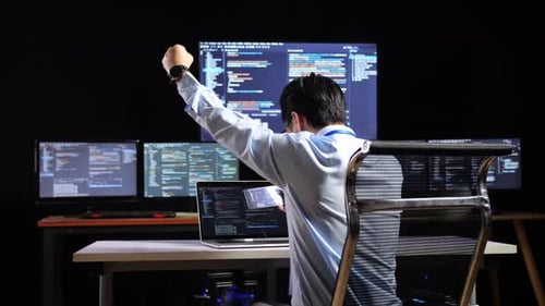 Software Developer Celebrating in Dark Office
