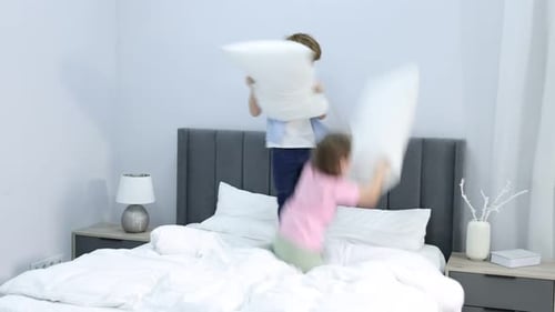 Des petits amis heureux se disputent des oreillers sur le lit à la maison. Activité ludique