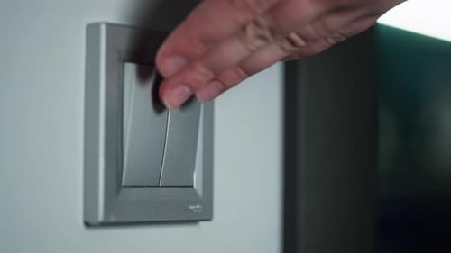 Vista aproximada das mãos de uma mulher tocando o interruptor de luz