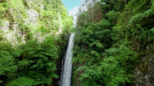 Majestic waterfall cascading down rocky cliffs surrounded by lush green forest