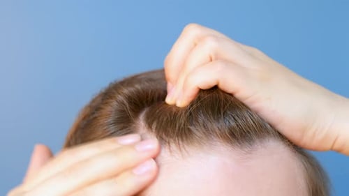 Girl touching her hair close-up on blue background, hair loss concept.