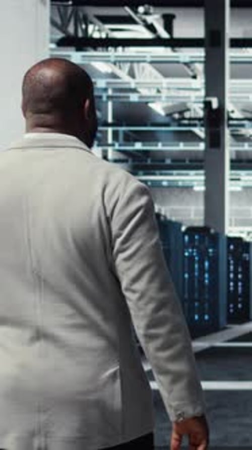 Vertical Video Admin Walking in High Tech Data Center Facility with Rows of Supercomputers