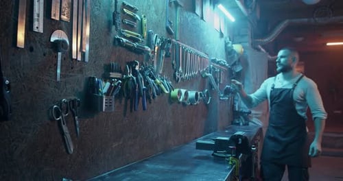 Man Selecting Wrench from Tool-Lined Workshop Wall