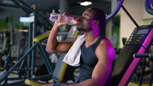 African American Sport Man Drinking Water in the Gym