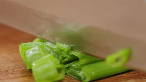 Chef Cutting Bunch of Green Onion Feathers By Knife on a Cutting Board on Professional Restaurant
