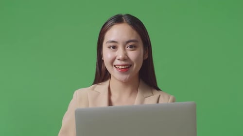 Close Up Of Asian Business Woman Using Laptop Computer And Smiling To Camera On Green Screen Studio