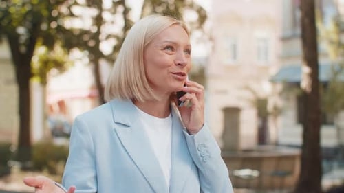Happy Mature Caucasian Businesswoman Lady Smiling Laughs While Talking on Smartphone on City Street