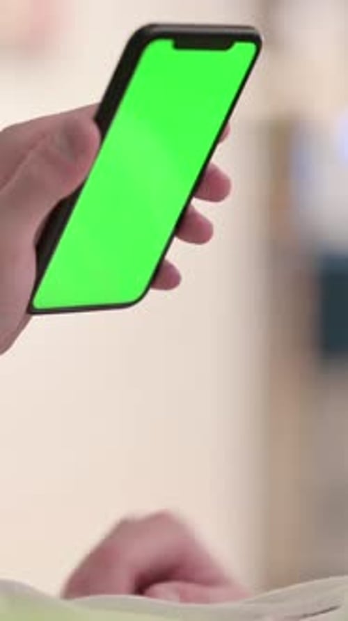 Hand Holding Smartphone with Green Screen Indoors