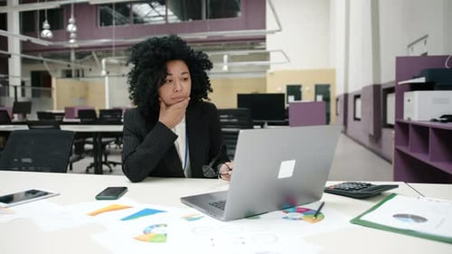 Woman Sitting at Desk Looking Concerned at Laptop