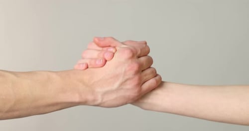 Two Hands Clasping with Affection on Light Background