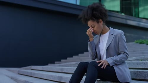 Woman with Headache Sitting on City Steps