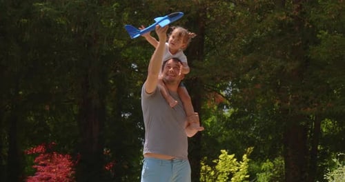 Dad and Son are Playing in the Park on a Summer Sunny Day Blue Plane in the Hands of a Teenager
