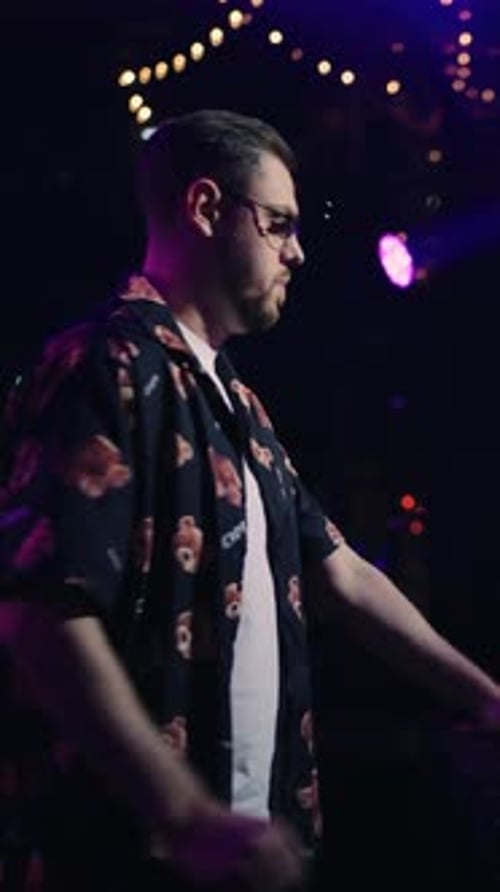 Electronic Music DJ Performing Live on Stage with Turntables Under Dramatic Club Lighting