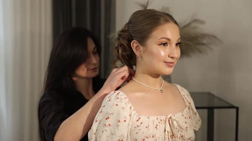 Woman is Fitted with Pearl Necklace by Woman