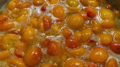 The process of making apricot jam in a metal pan. The jam is cooked in a pan.