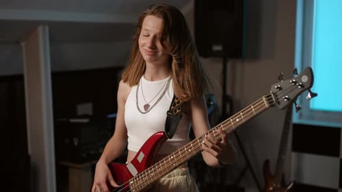 Slow Motion Portrait of a Young Girl Playing Her Favorite Rock Song on the Bass Guitar and Smiling